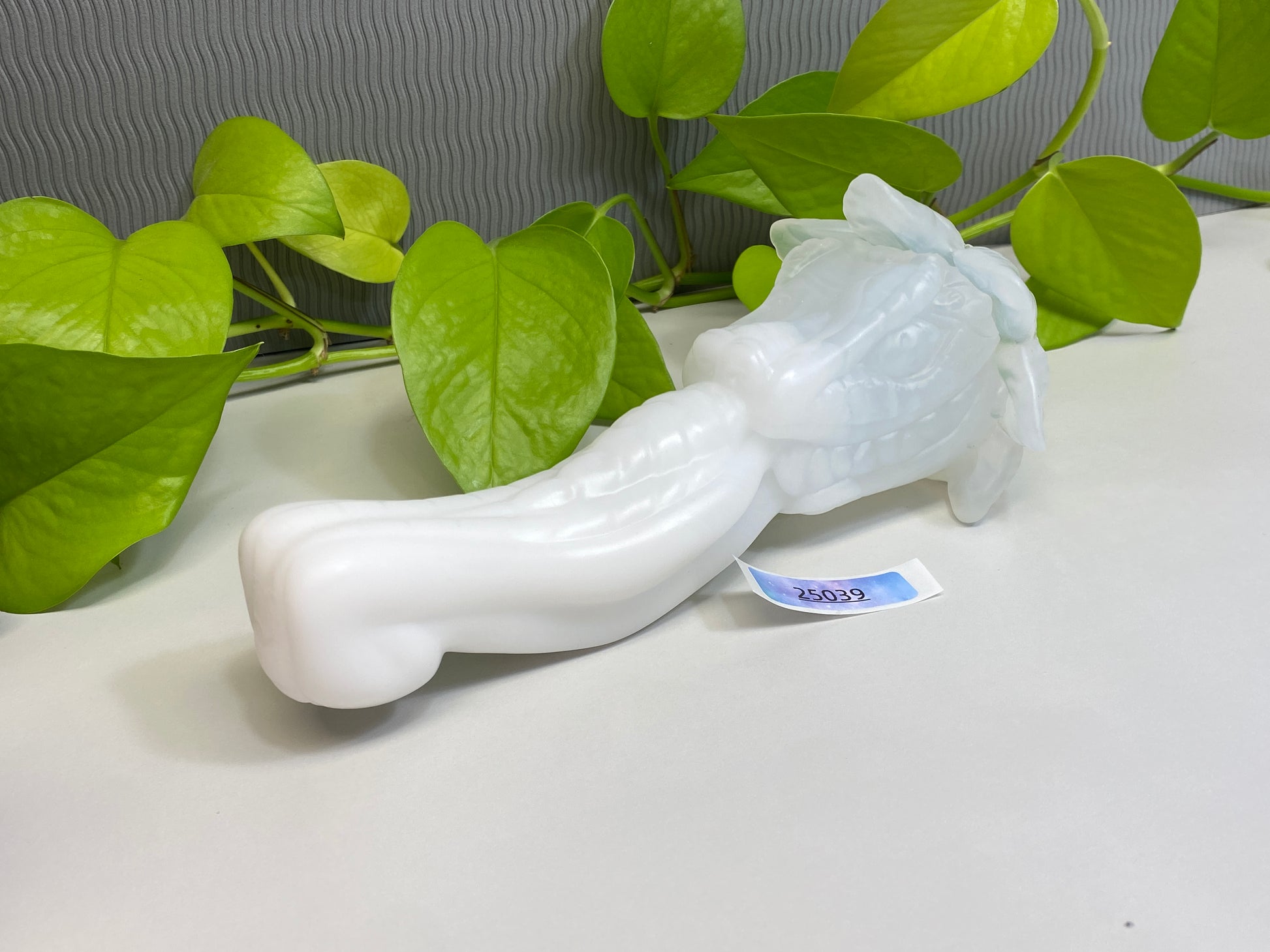 a white vase sitting on top of a table next to a green plant