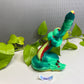 a green toy snake sitting on top of a green plant