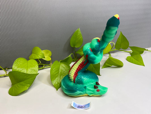 a green toy snake sitting on top of a green plant