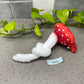 a red mushroom sitting on top of a counter next to a plant