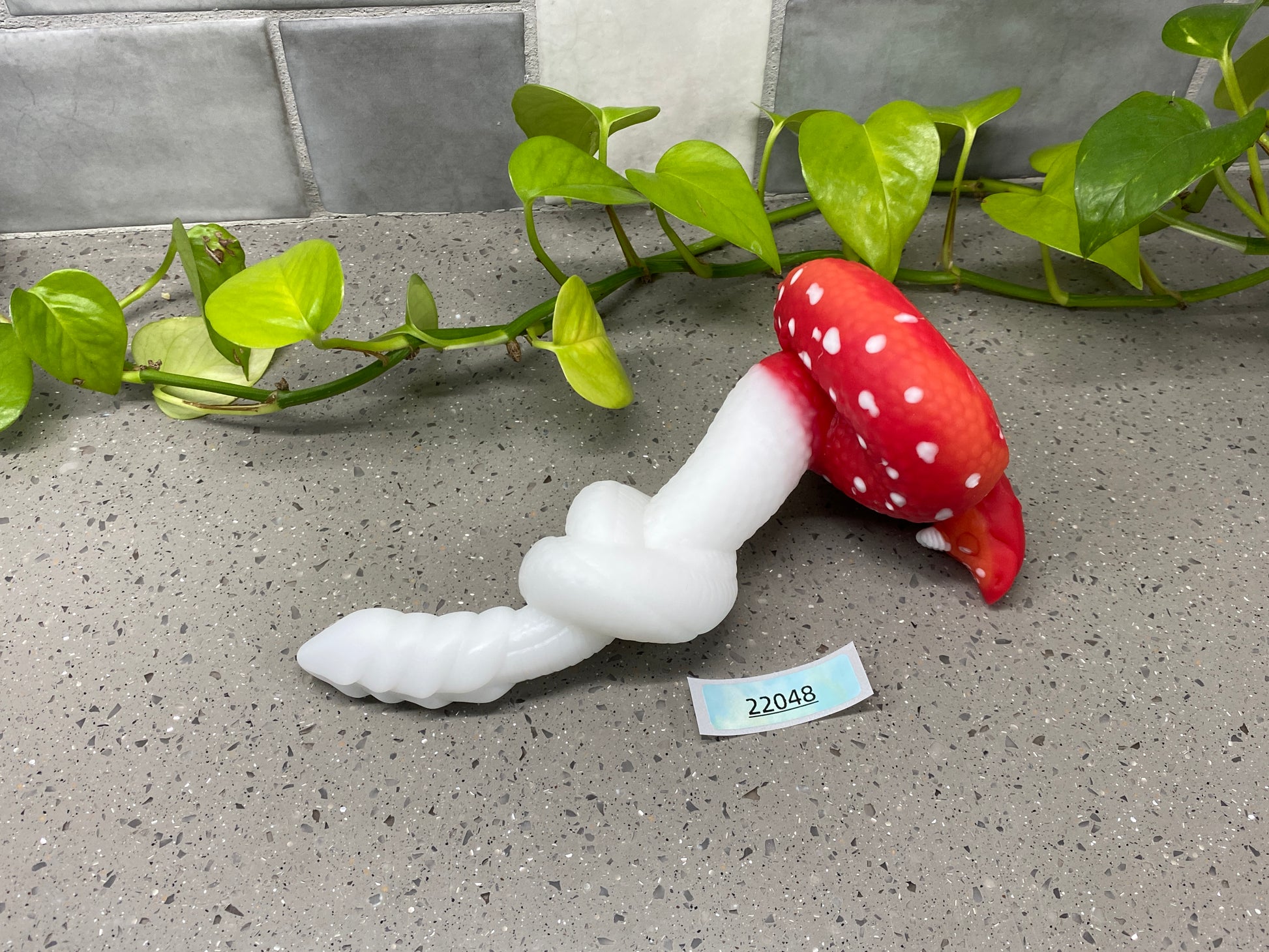 a red mushroom sitting on top of a counter next to a plant