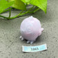 a pink pig figurine sitting next to a plant
