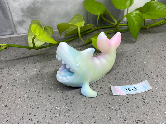 a small plastic toy dolphin next to a plant
