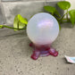 a glass ball sitting on top of a table next to a plant