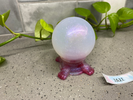 a glass ball sitting on top of a table next to a plant