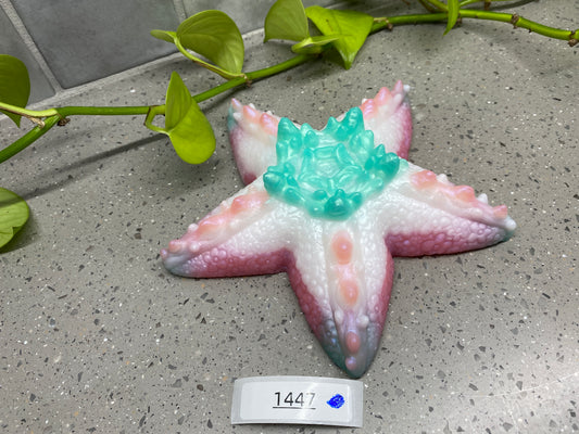 a ceramic starfish ornament sitting on a table next to a plant