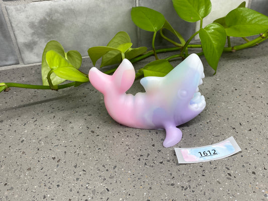 a ceramic figurine of a whale on a table next to a plant