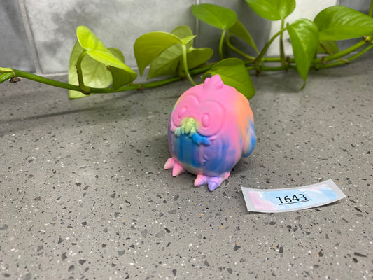 a small toy pig sitting on top of a table next to a plant