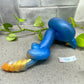 a blue and yellow toy laying on a counter next to a plant