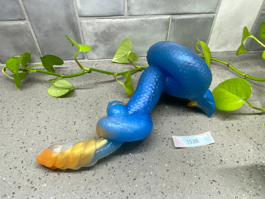 a blue and yellow toy laying on a counter next to a plant