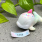 a white ceramic toy with a pink and blue horn