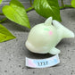 a small white ceramic animal sitting next to a green plant
