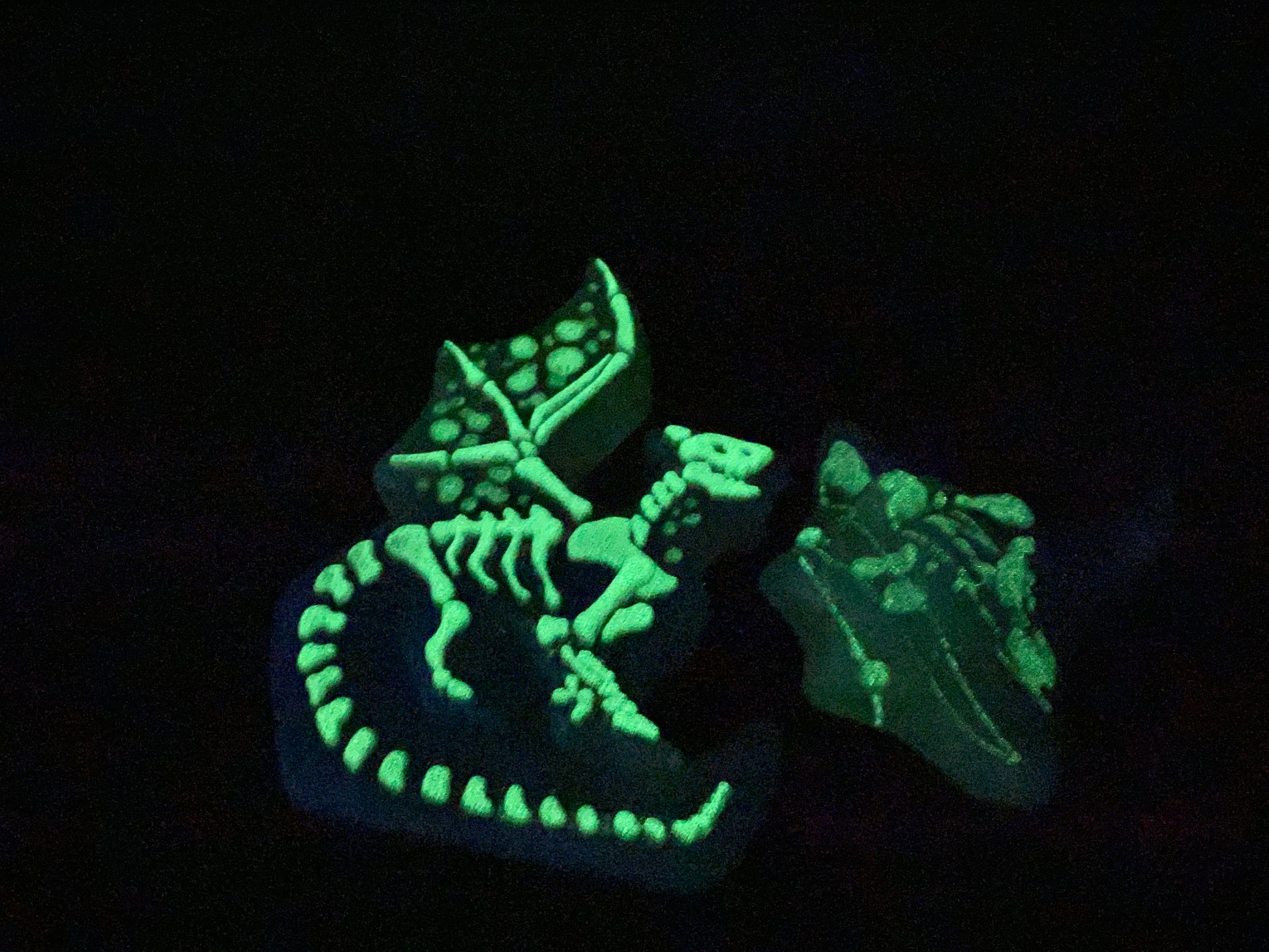 three glow - in - the - dark toys are sitting on a black surface