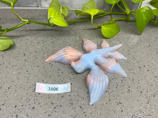 a blue bird figurine sitting on top of a table next to a plant