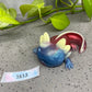 a blue and red dragon figurine next to a plant