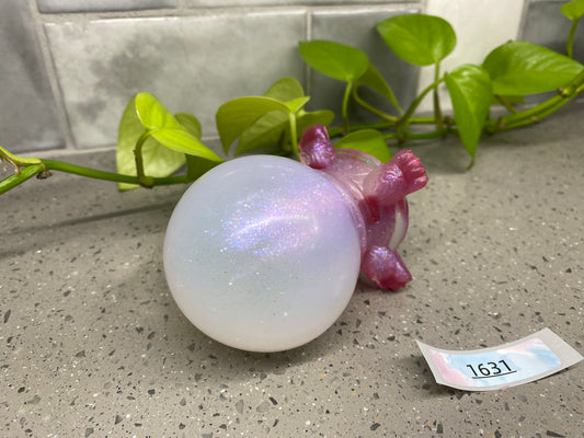 a white ball sitting on top of a counter next to a plant