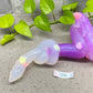 a purple plastic worm sitting on top of a table next to a plant