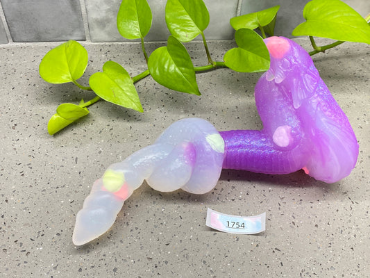a purple plastic worm sitting on top of a table next to a plant